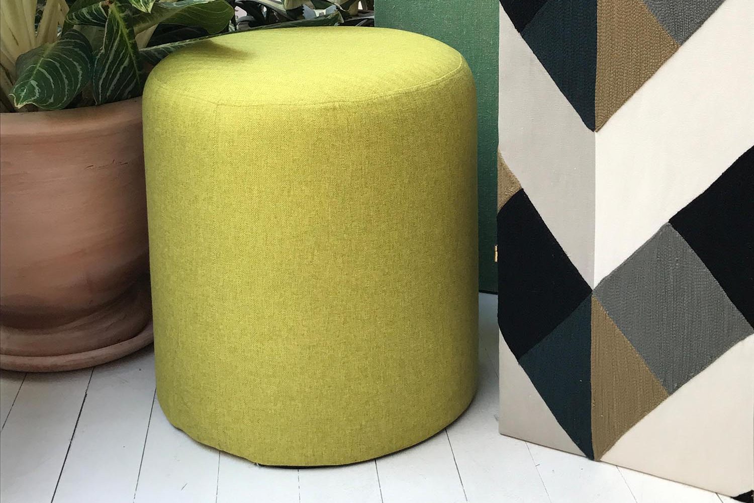 Boussac, Sherlock : pouf vert anis devant une tenture à chevrons
