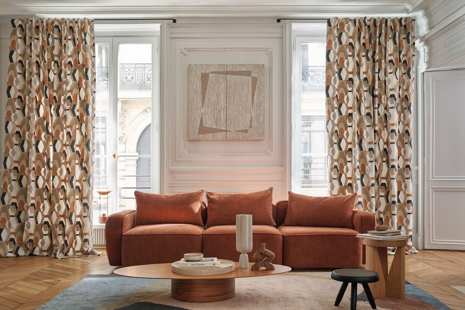 Casamance, Point de Vue : rideaux à motifs terracotta et canapé rouille dans un salon à moulures