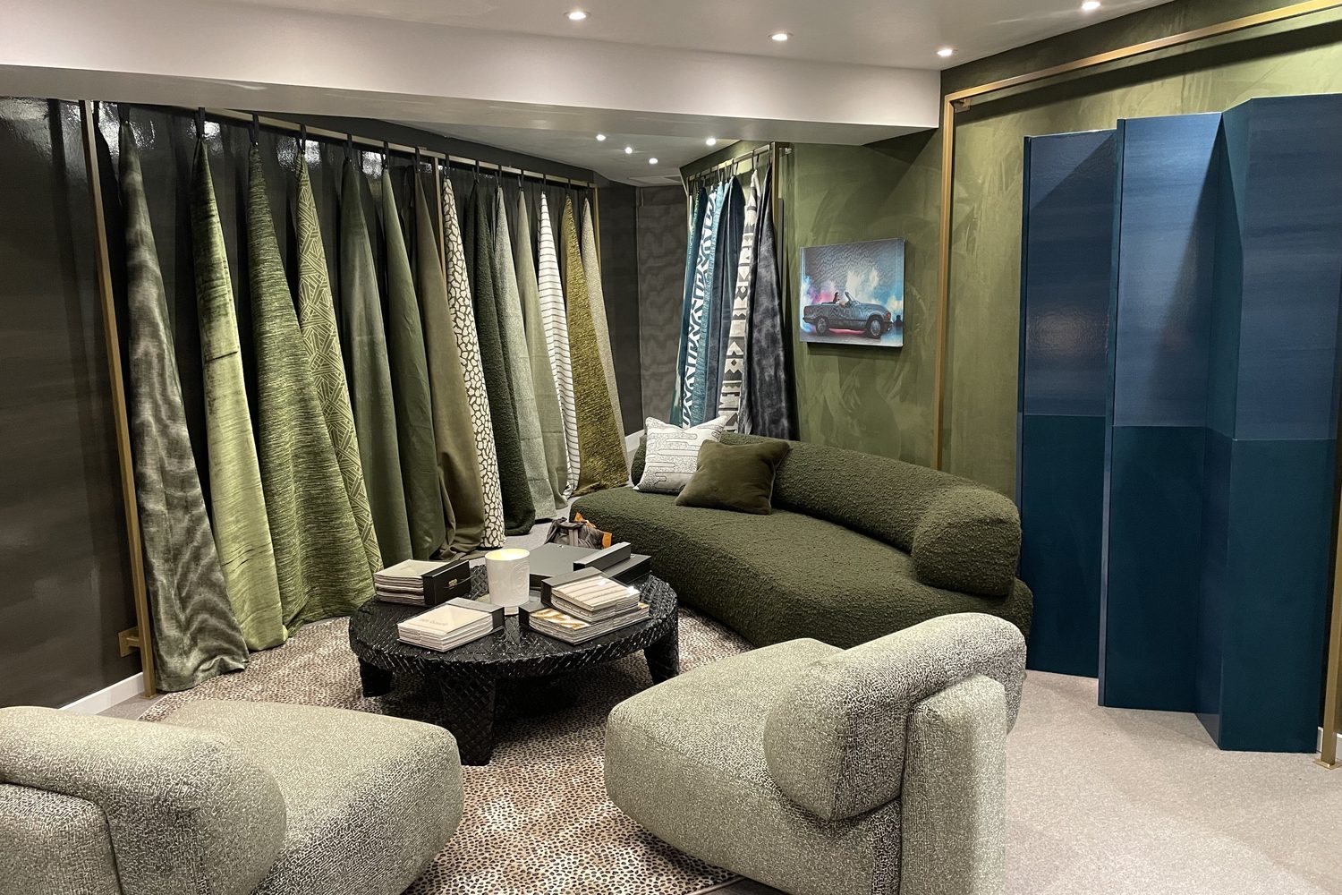 Romo : showroom aux rideaux de tissus verts, canapé bouclette vert et paravent bleu canard