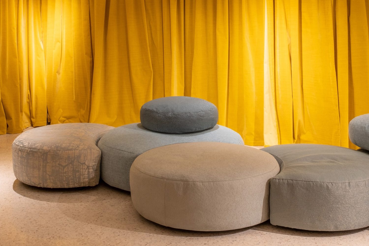 Rubelli : rideaux jaune safran derrière des poufs arrondis gris et beige
