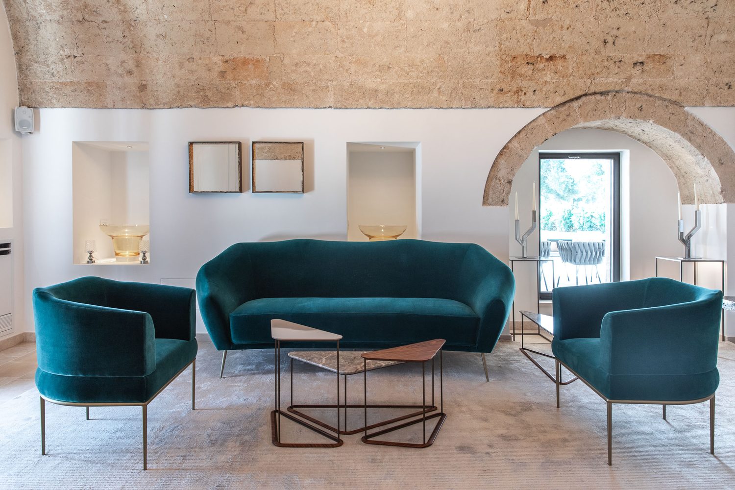 Rubelli : canapé et fauteuils en velours bleu canard sous une voûte de pierre