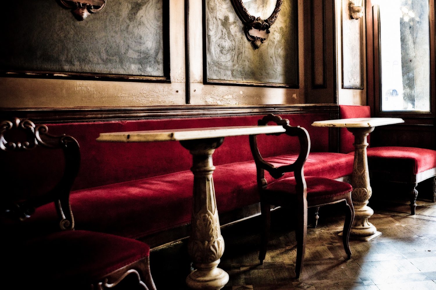 Rubelli : banquettes de velours rouge dans un café aux boiseries anciennes
