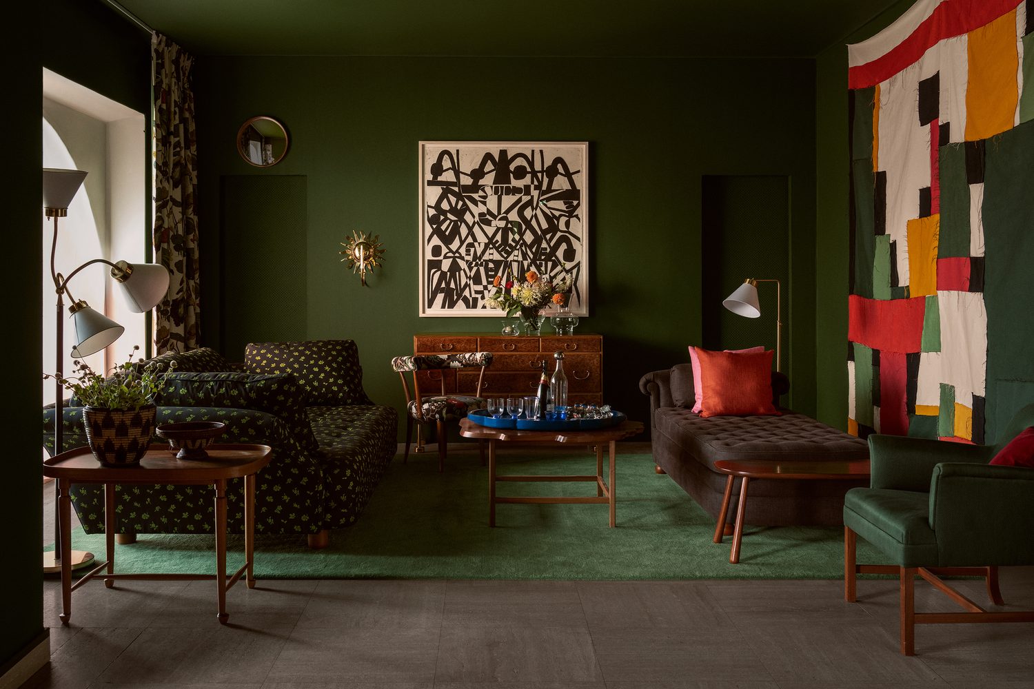 Sahco : salon aux murs vert bouteille, sièges à motifs et touches de rouge